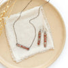 The andesine beaded bar earrings styled with the matching necklace on a tan plate with linen and dried grass