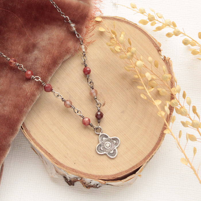 The andesine mini talara necklace styled on wood with orange velvet and dried grass