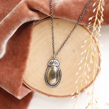 The apache gold necklace styled on wood with orange velvet and dried grass