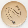 The apache gold necklace styled on a tan plate to show the adjustable lobster clasp closure