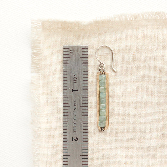 An apatite beaded bronze bar earring next to a ruler for size reference