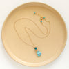 The apatite and turquoise necklace styled on a tan plate to show the adjustable lobster clasp closure
