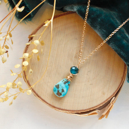 The apatite and turquoise necklace styled on wood with blue velvet and dried grass