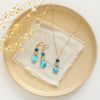 The apatite and turquoise drop earrings styled on a tan plate with the matching necklace