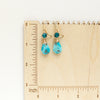 The apatite and turquoise drop earrings on a wooden ruler for size reference