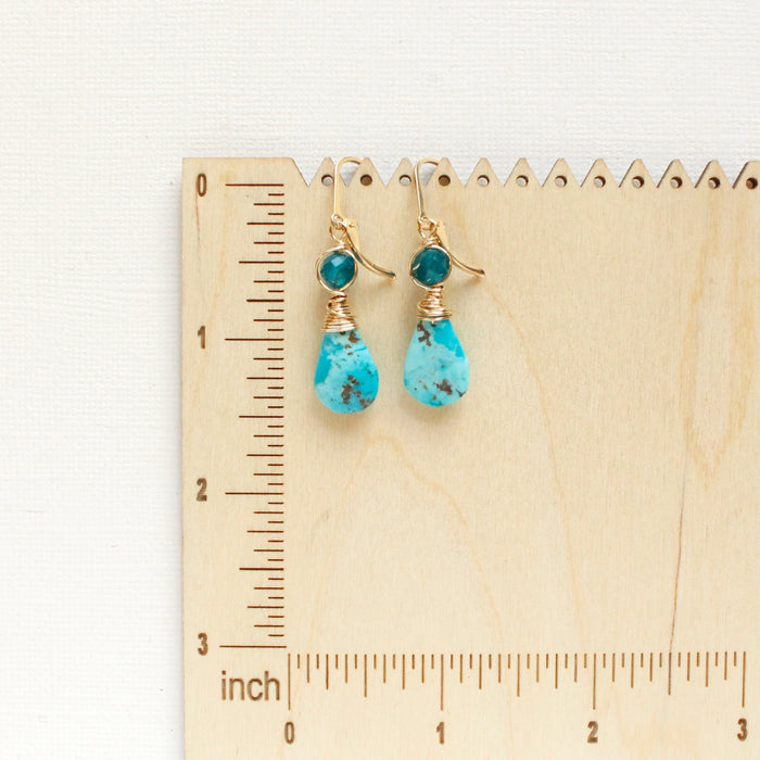 The apatite and turquoise drop earrings on a wooden ruler for size reference
