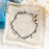 The aquamarine charm bracelet styled on tan linen with blue velvet and dried grass