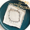 The aquamarine charm bracelet styled on a blue plate with linen and dried grass