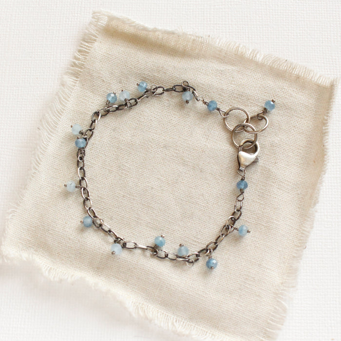 The aquamarine charm bracelet styled on tan linen