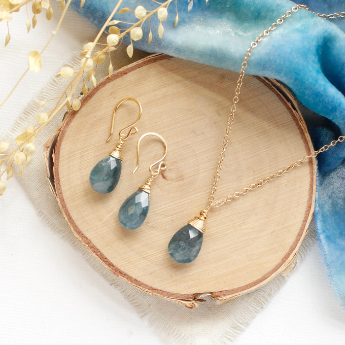 The aquamarine drop earrings styled on the matching necklace on wood with blue velvet and dried grass