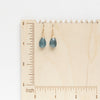 The aquamarine drop earrings styled on a wooden ruler for size reference