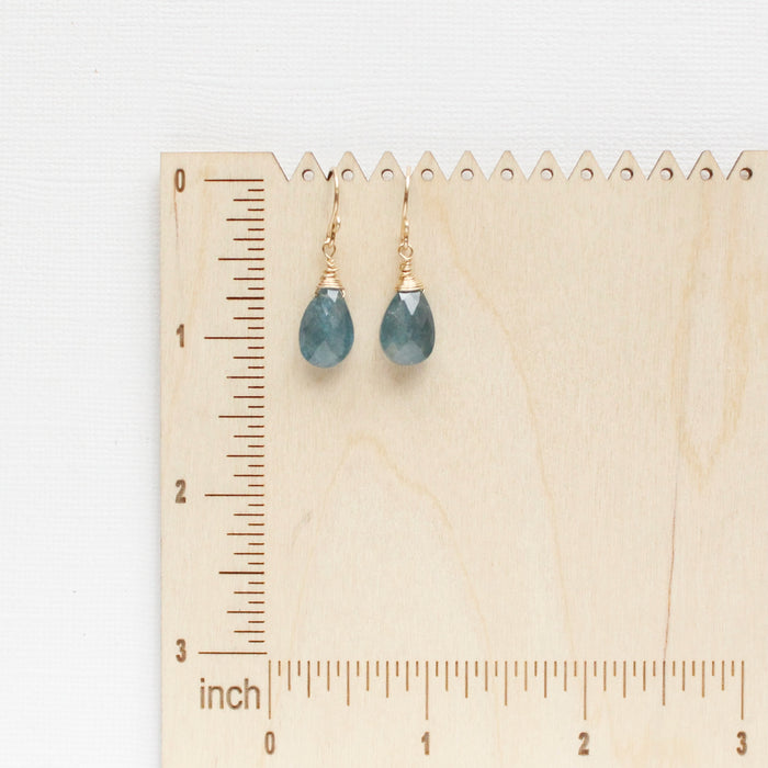 The aquamarine drop earrings styled on a wooden ruler for size reference