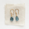 The aquamarine drop earrings styled on tan linen