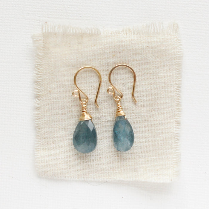 The aquamarine drop earrings styled on tan linen