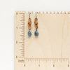 The aquamarine leather earrings styled on a wooden ruler for size reference