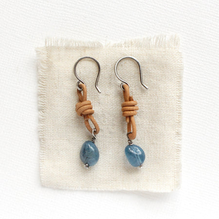 The aquamarine leather earrings styled on tan linen