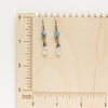 The aquamarine and moonstone earrings styled on a wooden ruler
