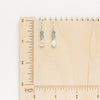 The aquamarine and moonstone earrings styled on a wooden ruler for size reference