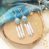 The aquamarine and pearl chandelier earrings styled on wood with blue velvet and dried grass