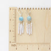 The aquamarine and pearl chandelier earrings on a wooden ruler for size reference