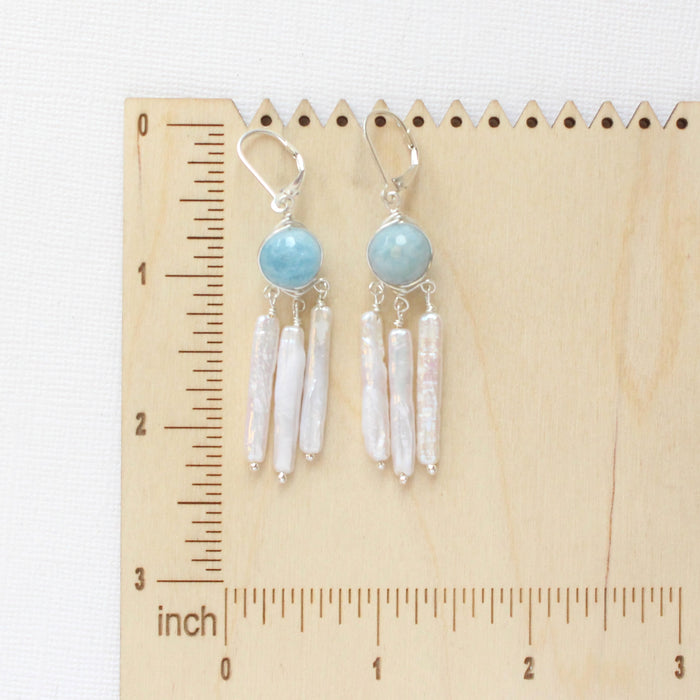 The aquamarine and pearl chandelier earrings on a wooden ruler for size reference