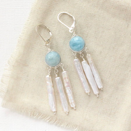 The aquamarine and pearl chandelier earrings styled on tan linen