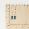 The aquamarine and disc chain earrings styled on a wooden ruler
