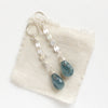 The aquamarine drop and silver disc long earrings styled on tan linen