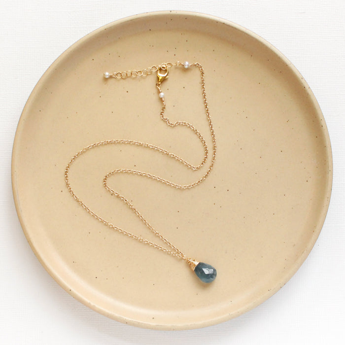 The aquamarine drop necklace styled on a tan plate to show the adjustable lobster clasp closure