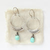 The asmi blade turquoise drop earrings styled on tan linen