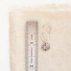 A aspen leaf hoop earring next to ruler for size reference