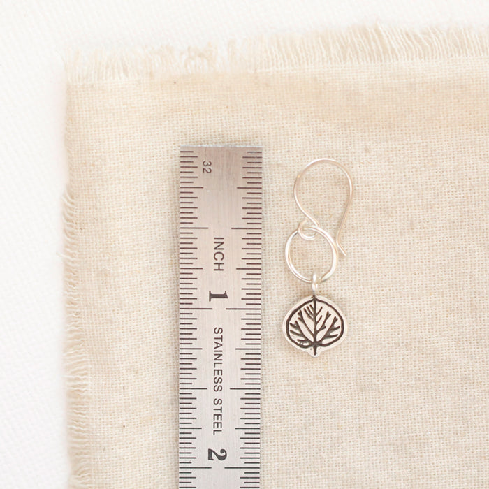 A aspen leaf hoop earring next to ruler for size reference