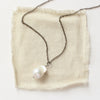 The baroque pearl necklace styled on tan linen