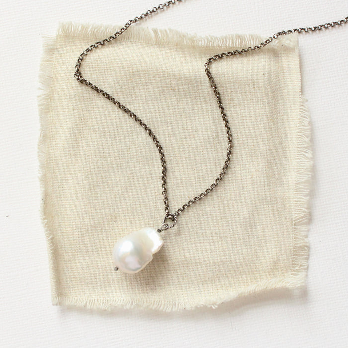 The baroque pearl necklace styled on tan linen