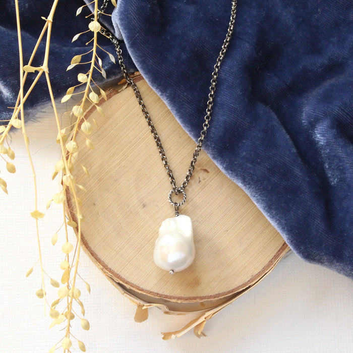 The baroque pearl necklace styled on wood with blue velvet and dried grass