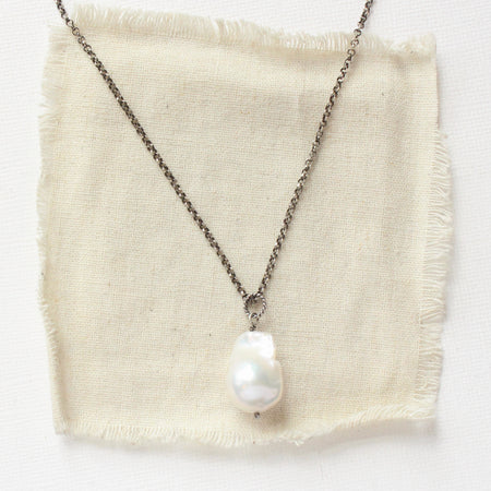 The baroque pearl necklace styled on tan linen