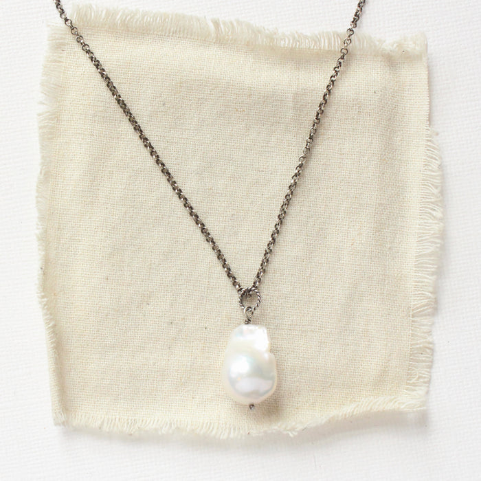 The baroque pearl necklace styled on tan linen