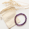 The beaded amethyst stretch bracelet styled with the branded canvas bad and dried grass