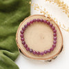 The beaded ruby stretch bracelet styled on wood with green velvet and dried grass