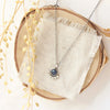 The beaded sapphire necklace styled on wood with linen and dried grass