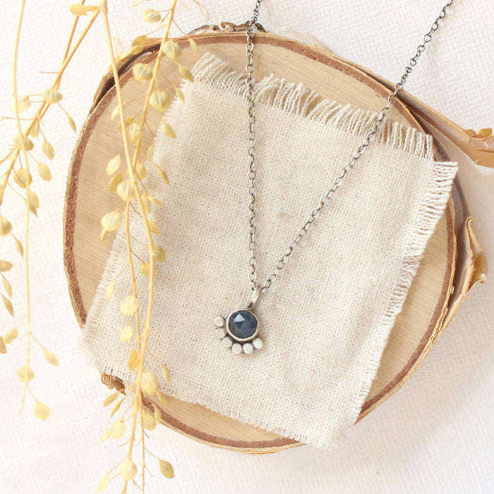 The beaded sapphire necklace styled on wood with linen and dried grass