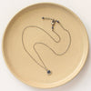 The beaded sapphire necklace styled on a tan plate to show the adjustable lobster clasp closure