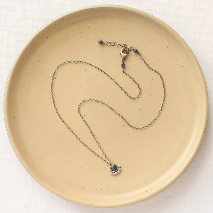The beaded sapphire necklace styled on a tan plate to show the adjustable lobster clasp closure