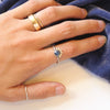 The beaded sapphire ring being worn on a hand