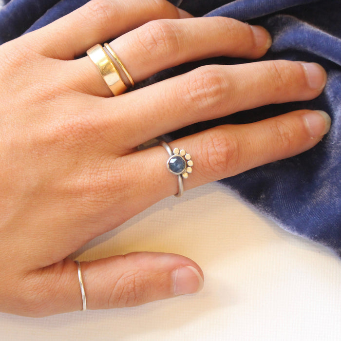 The beaded sapphire ring being worn on a hand