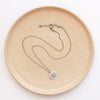 The big musana necklace styled on a tan plate to show the adjustable lobster clasp closure