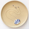 The birds of a feather vintage plate necklace styled on a tan plate to show the adjustable lobster clasp closure