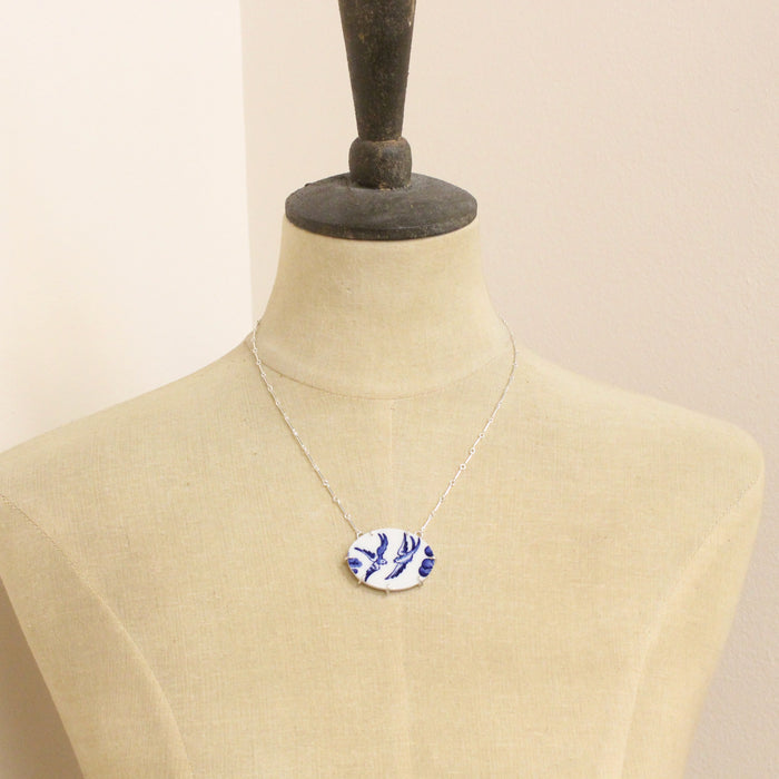A mannequin wearing the birds of a feather vintage plate necklace