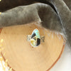 The black jack turquoise ring styled on wood with gray velvet and dried grass