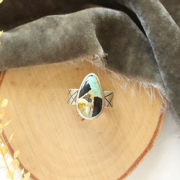 The black jack turquoise ring styled on wood with gray velvet and dried grass